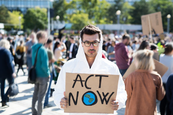 Portrait of man with placard and protective suit on global strike for climate change.