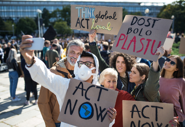 People with placards and protective suit on global strike for climate change, taking selfie.