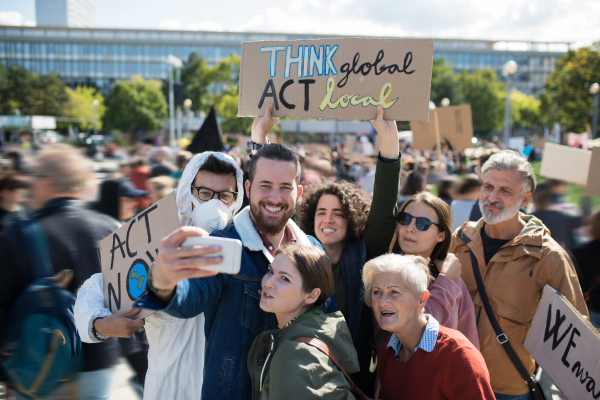 People with placards and posters on a global strike for climate change, taking selfie.