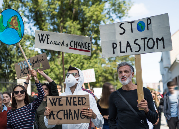 People with placards and a protective suit on a global strike for climate change.