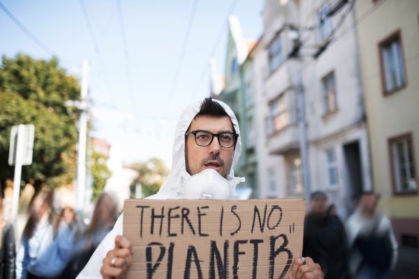 A portrait of man with protective suit and placard on global strike for climate change.