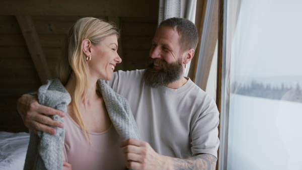 A Happy mature couple in love enjoying holiday in a mountain hut indoors.