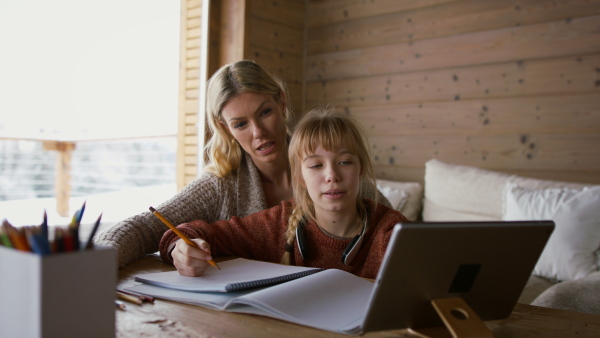 A mother with small daughter doing homework indoors at home, home scholl concept.