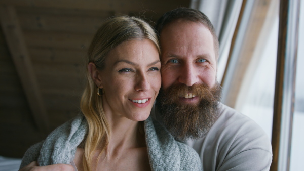 A close up of happy mature couple in love enjoying holiday in mountain hut indoors.