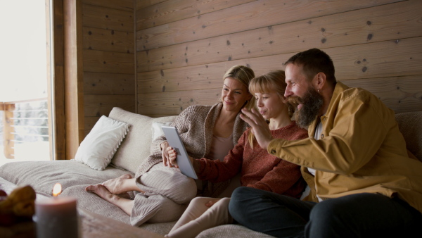 A family with small daughter making video call with tablet indoors, winter holiday in private apartment.