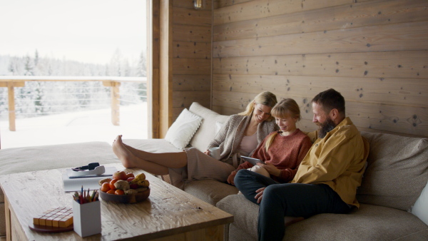 A family with small daughter making video call with tablet indoors, winter holiday in private apartment.