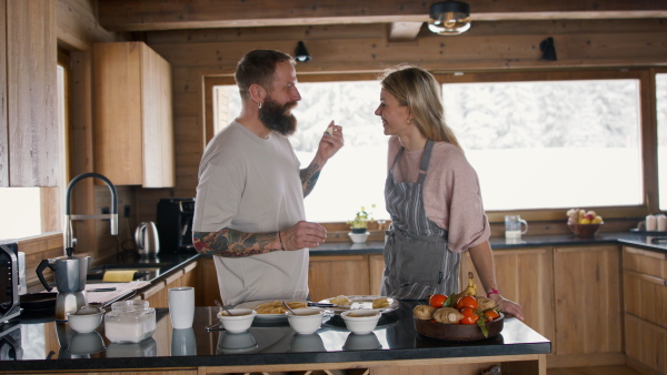 A happy mature couple in love cooking together indoors, winter holiday in private apartment.