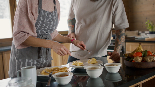 A happy mature couple in love cooking together indoors, winter holiday in private apartment.