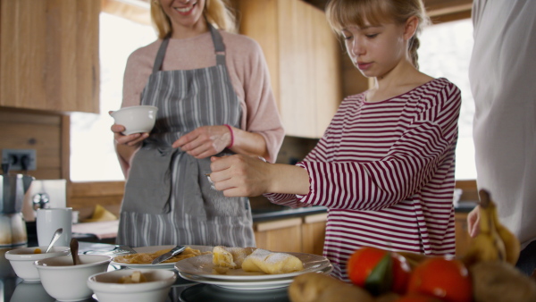 Happy family with small daughter cooking indoors, winter holiday in private apartment.