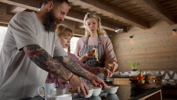 Happy family with small daughter cooking indoors, winter holiday in private apartment.