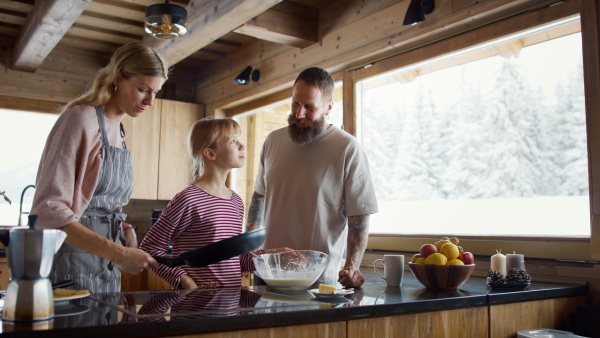 Happy family with small daughter cooking indoors, winter holiday in private apartment.