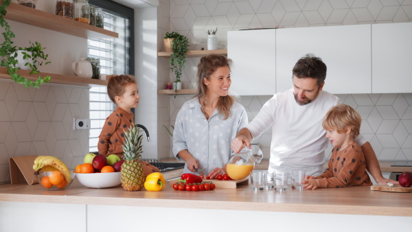 A happy young family with little children cooking together at home.