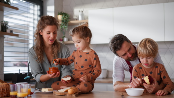 A happy young family with little children cooking together at home.