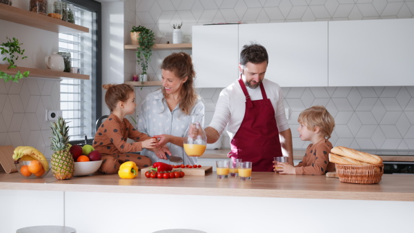 A happy young family with little children cooking together at home.