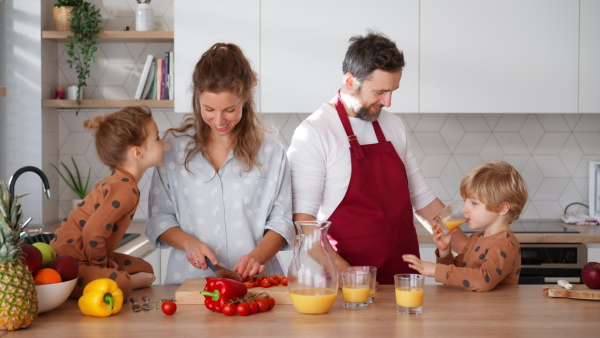 A happy young family with little children cooking together at home.