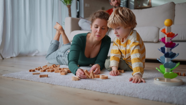 A mother playing eith her little son with wodden montessori toys at home.