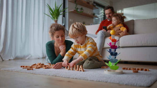 A mother playing with her little son with wodden montessori toys at home.