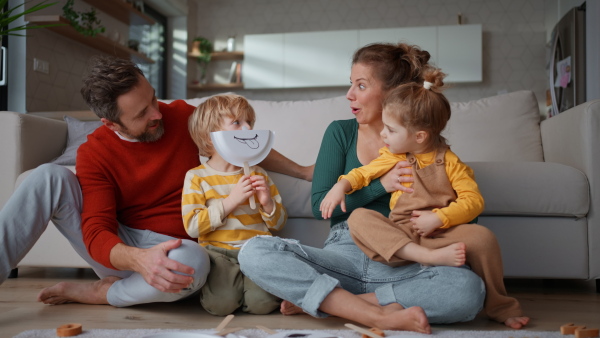 Little children playing with face masks with parents on sofa at home