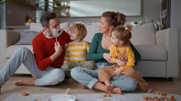 Little children playing with face masks with parents on sofa at home