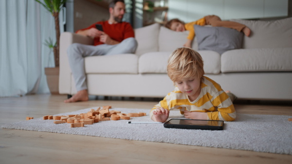 A little boy lying on floor and using tablet at home