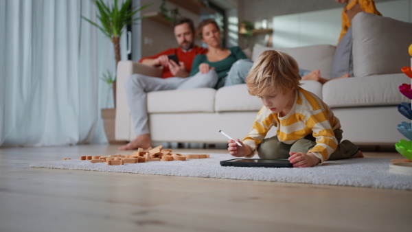 A little boy lying on floor and using tablet at home