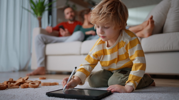 A little boy lying on floor and using tablet at home