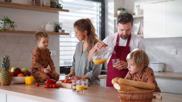 A happy young family with little children cooking together at home.