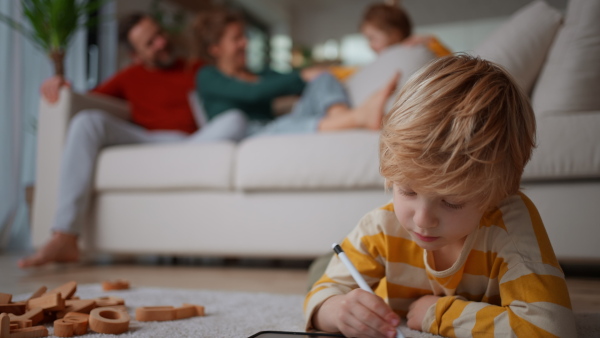 A little boy lying on floor and using tablet at home