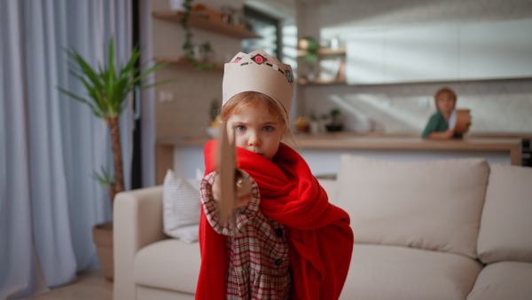 A little girl looking at camera when playing with diy swords at home