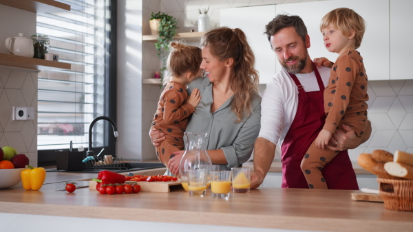 A happy young family with little children cooking together at home.