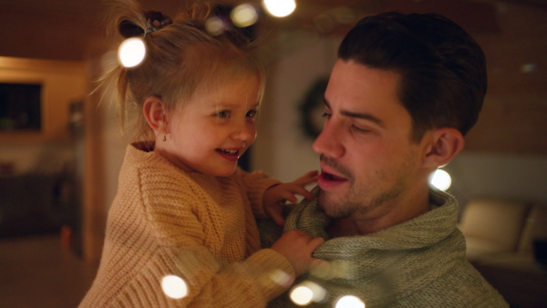 A young father enjoying time together with little daughter at home during winter holidays.