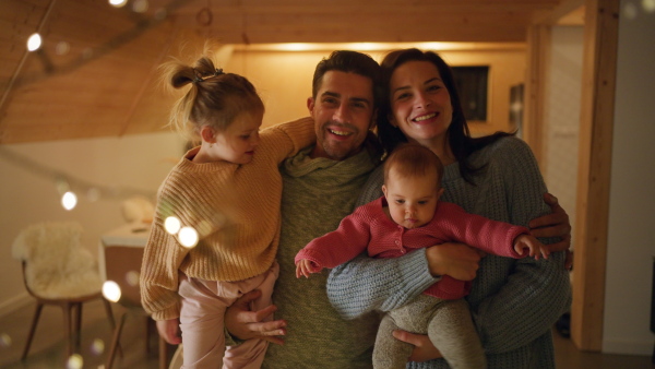 A happy young family with small children in cabin on holiday, looking at camera.