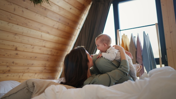 A young mother playing with her baby daughter at home.