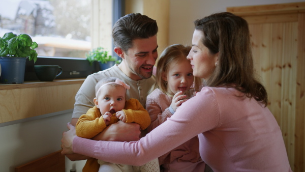 A happy young family with small children hugging at home