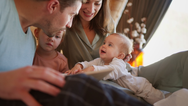 A happy young family with small children reading book in cabin on holiday.