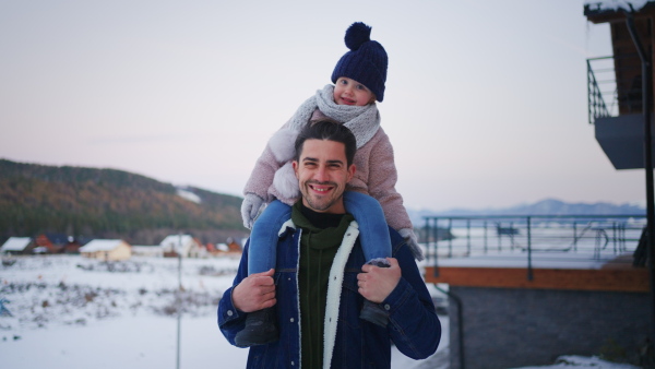 A happy young father on winter holiday with small child outdoors in snowy nature.