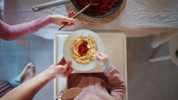 A top view of mother serving meal to his little daughter at home.