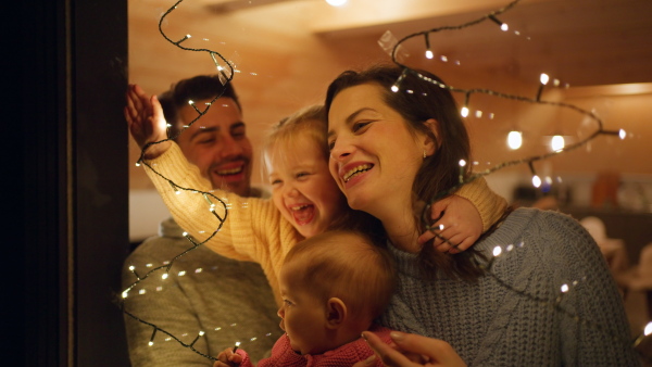 A happy young family with small children in cabin on holiday, looking at camera.