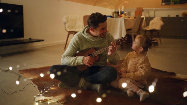 A young father enjoying time together with little daughter at home during winter holidays.