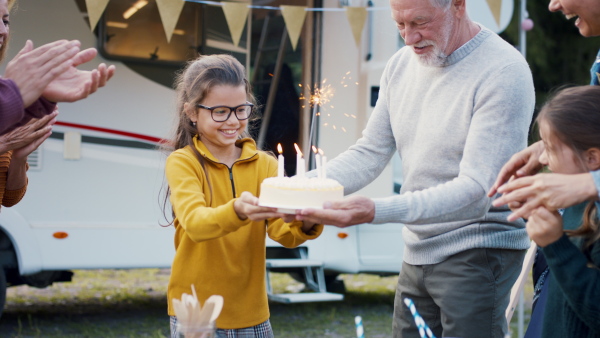 A multi-generation family celebrating birthday outdoors at campsite, caravan holiday trip.