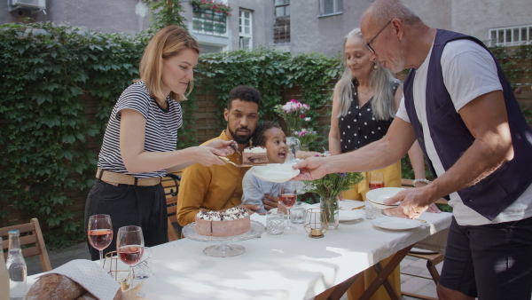 A multiracial three generations family celebrating birthday outdoors in back yard.