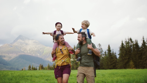 Front view of family with small children hiking outdoors in summer nature.