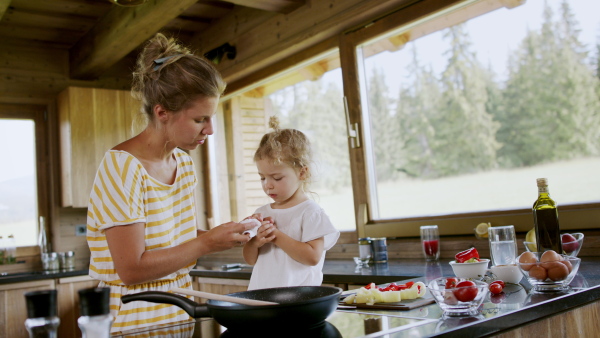 A mother blowing her little daughter's bleeding finger cut with knife at home.