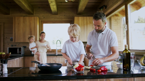 A family with small children cooking indoors, holiday in private apartment.