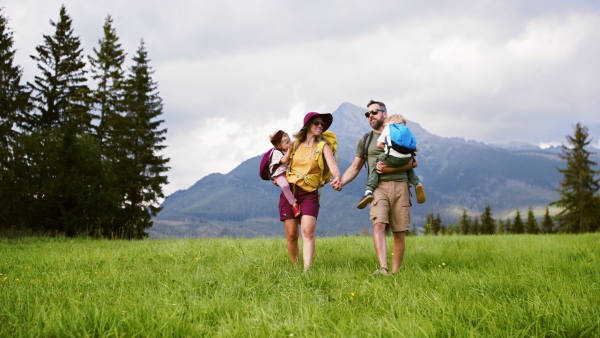 A family with small children hiking outdoors in summer nature.