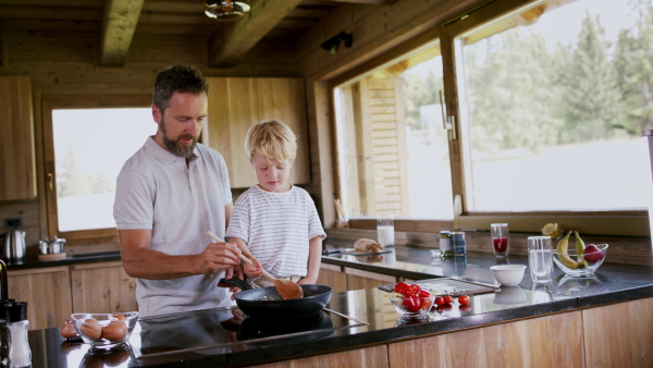 A father with small son cooking together in kitchen.