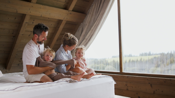 Parents putting on pyjamas to litte children on a bed at home.