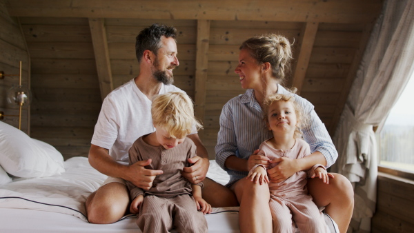 A happy young family with small children having fun in bed on holiday.