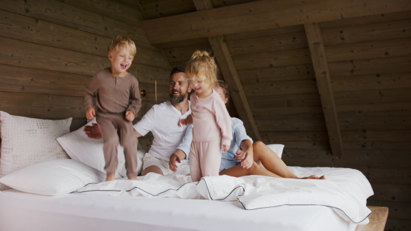 A happy young family with small children having fun in bed on holiday.