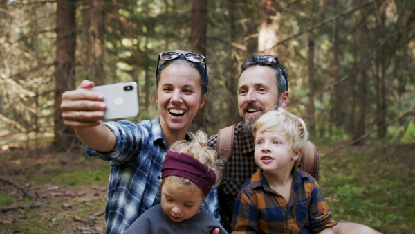 A family with small children having picnic in summer forest and taking selfie.